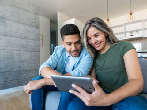 Young, multicultural man and woman watch TV content on a tablet device