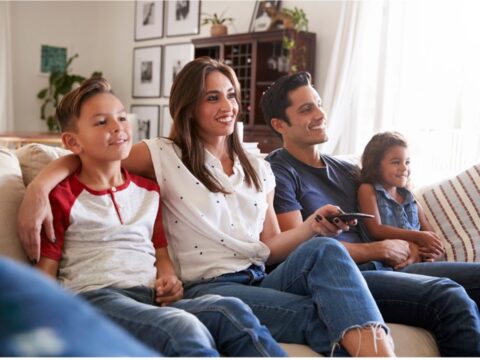 hispanic American family on the couch happily watching tv