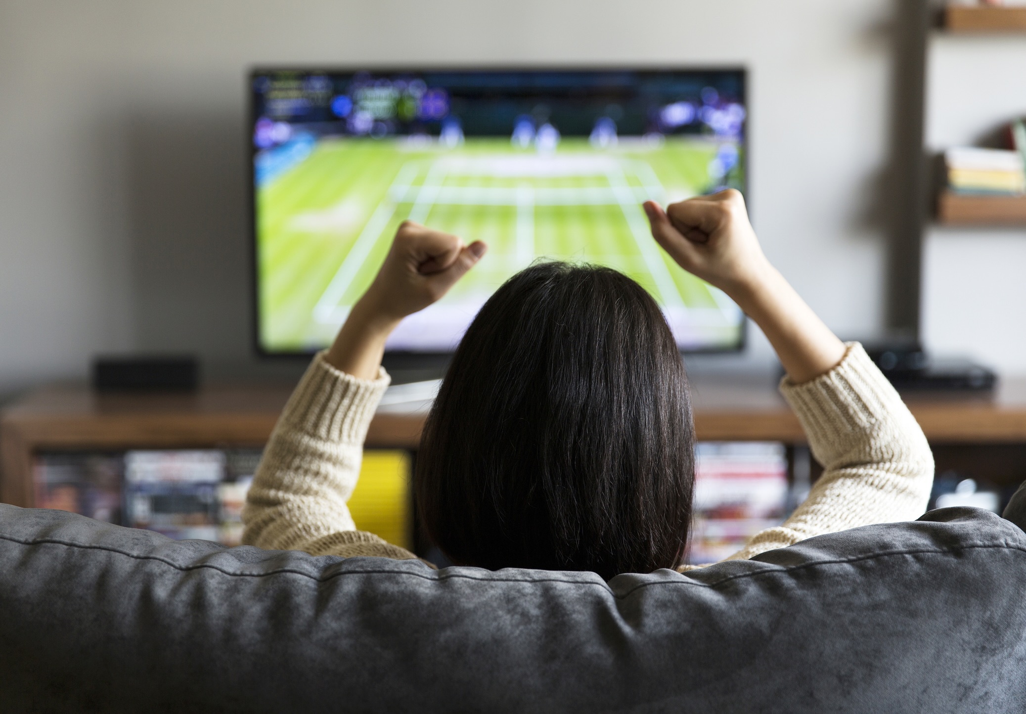 young woman watching Tennis on television and cheering young woman watching Tennis on television and cheering
